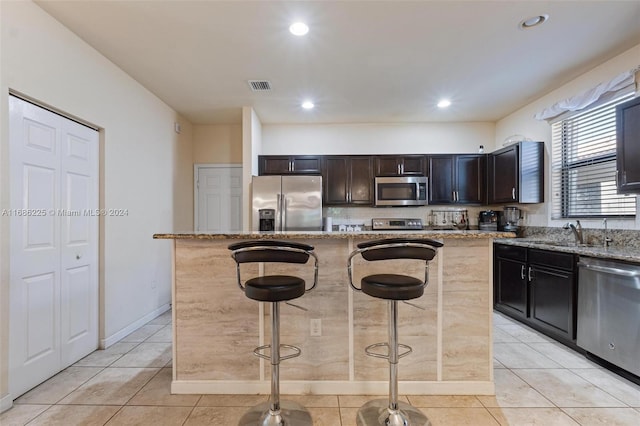 kitchen with light stone countertops, a center island, and stainless steel appliances