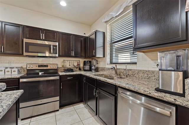 kitchen with light stone countertops, dark brown cabinets, stainless steel appliances, and sink