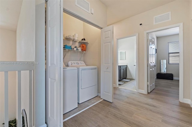 laundry area with light hardwood / wood-style floors and separate washer and dryer