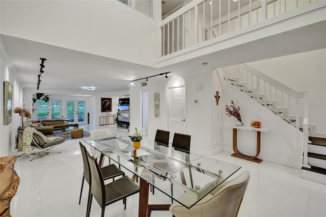 tiled dining space with a high ceiling, stairway, and track lighting