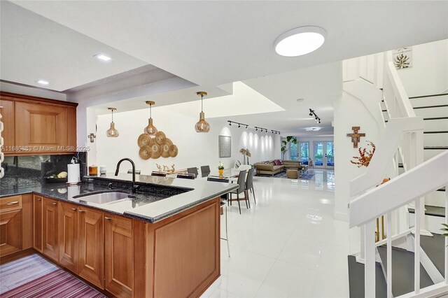 kitchen with kitchen peninsula, decorative backsplash, sink, light tile patterned floors, and pendant lighting