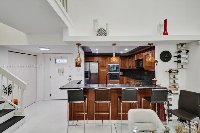 kitchen featuring tasteful backsplash, kitchen peninsula, decorative light fixtures, a breakfast bar, and black appliances