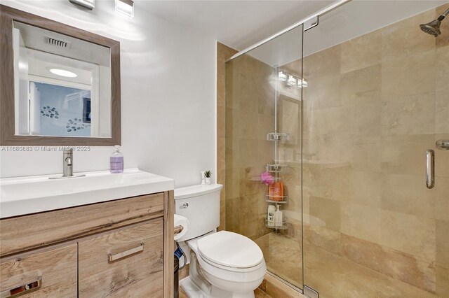 bathroom featuring vanity, an enclosed shower, and toilet