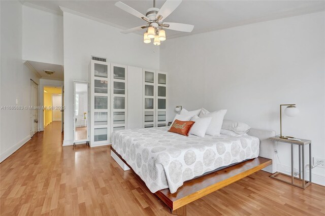 bedroom featuring ceiling fan, a towering ceiling, and wood-type flooring