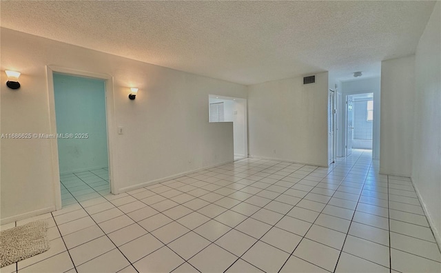 spare room with light tile patterned floors, visible vents, and a textured ceiling