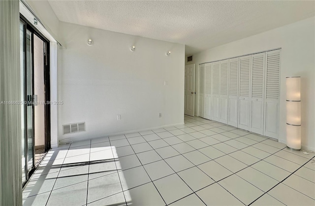 unfurnished bedroom featuring a textured ceiling, multiple windows, visible vents, and a closet