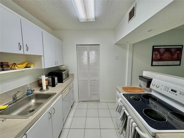 kitchen featuring sink, light tile patterned floors, white cabinetry, a textured ceiling, and white appliances