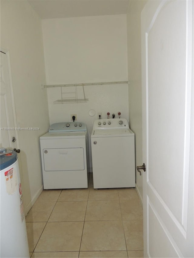 clothes washing area with washing machine and dryer, gas water heater, and light tile patterned floors