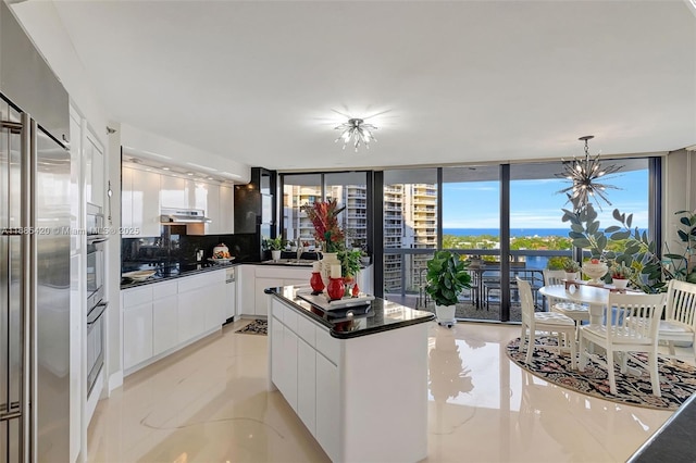 kitchen with tasteful backsplash, a wealth of natural light, decorative light fixtures, and white cabinets