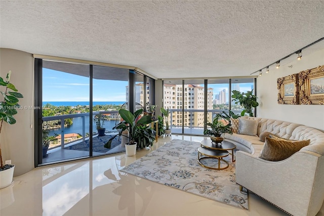 living room with a water view, a wall of windows, and a textured ceiling