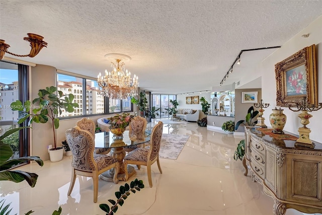 dining space featuring track lighting, a textured ceiling, and an inviting chandelier