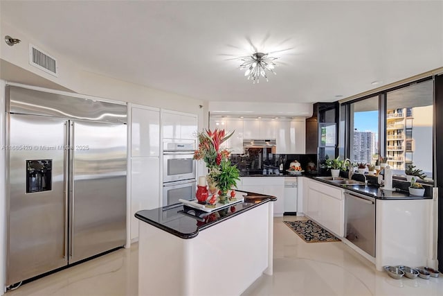 kitchen featuring tasteful backsplash, white cabinetry, sink, expansive windows, and stainless steel appliances