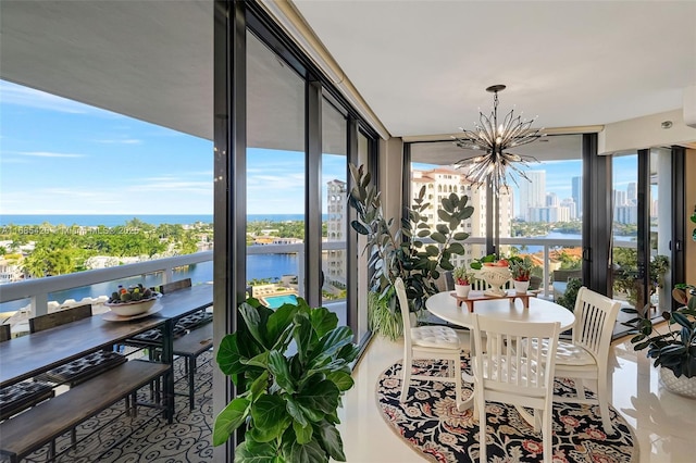 sunroom featuring a water view and a notable chandelier