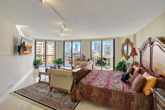 bedroom with expansive windows, access to outside, rail lighting, and a textured ceiling