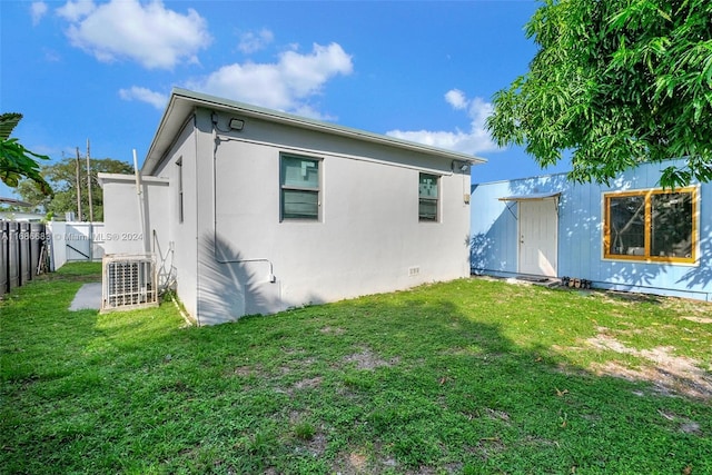 back of property featuring central air condition unit, a storage shed, and a yard