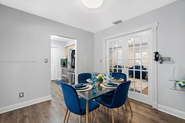 dining area with dark wood-type flooring, a textured ceiling, and french doors