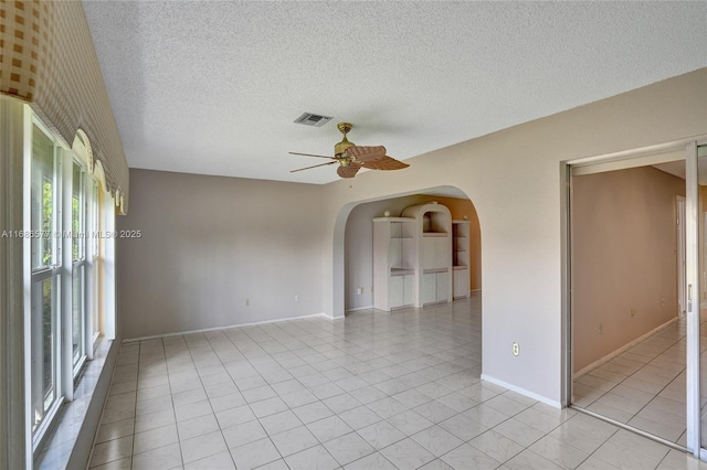 unfurnished room with a textured ceiling, ceiling fan, and light tile patterned flooring