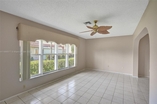 empty room featuring ceiling fan, light tile patterned floors, and a textured ceiling