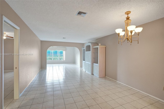 tiled spare room with a textured ceiling and ceiling fan with notable chandelier