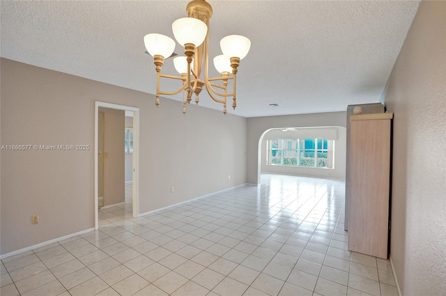 tiled empty room with a chandelier and a textured ceiling