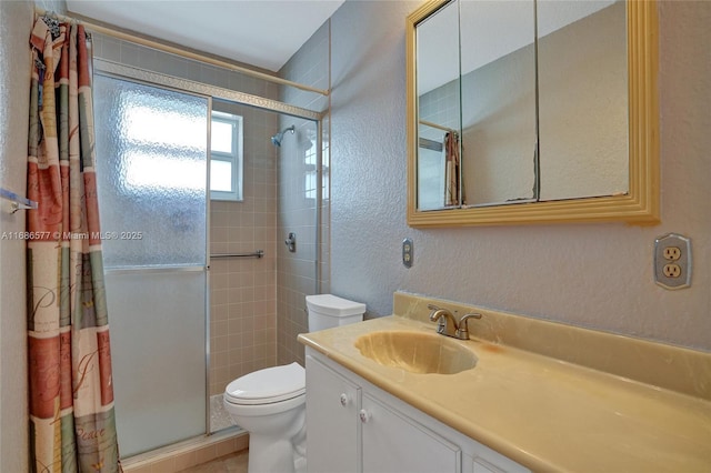 bathroom with toilet, vanity, and tiled shower