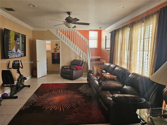 living room featuring ceiling fan, light tile patterned floors, ornamental molding, and a textured ceiling