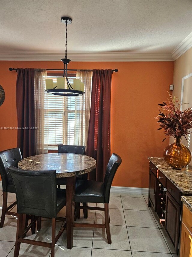 dining area featuring ornamental molding, a textured ceiling, and light tile patterned floors