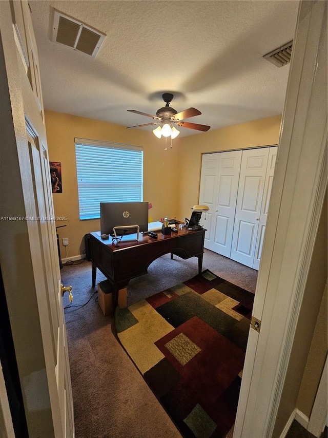 carpeted office space featuring a textured ceiling and ceiling fan