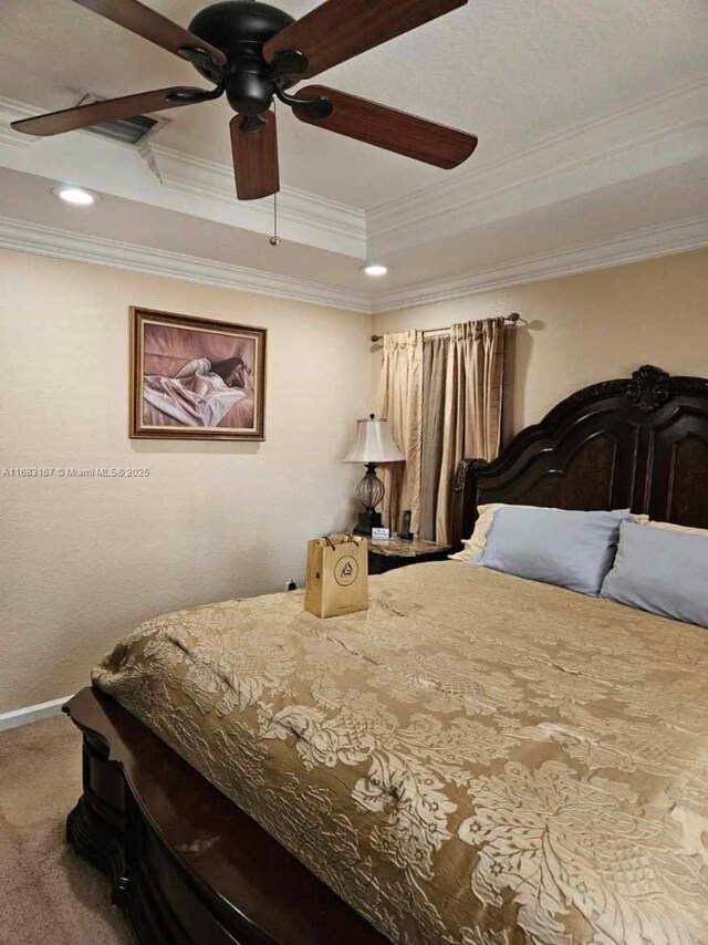 bedroom with ceiling fan, carpet flooring, ornamental molding, and a tray ceiling