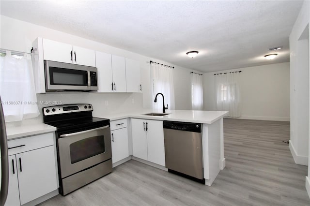 kitchen featuring kitchen peninsula, stainless steel appliances, white cabinetry, and sink