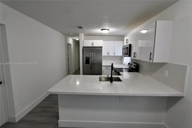 kitchen with kitchen peninsula, stainless steel appliances, white cabinets, and sink