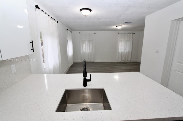 kitchen with sink, white cabinets, a textured ceiling, and backsplash