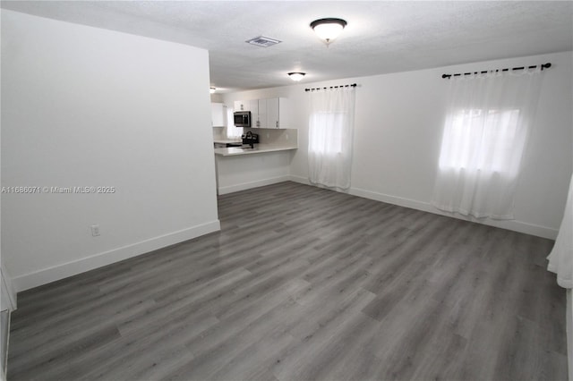 unfurnished living room with a textured ceiling and dark hardwood / wood-style floors