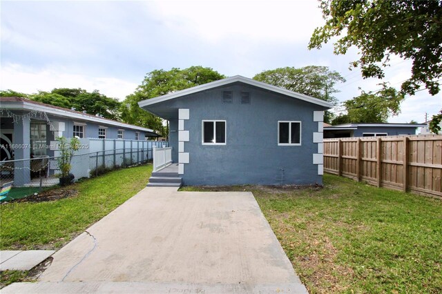 back of house with a patio and a lawn