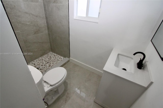 bathroom with toilet, tiled shower, and sink