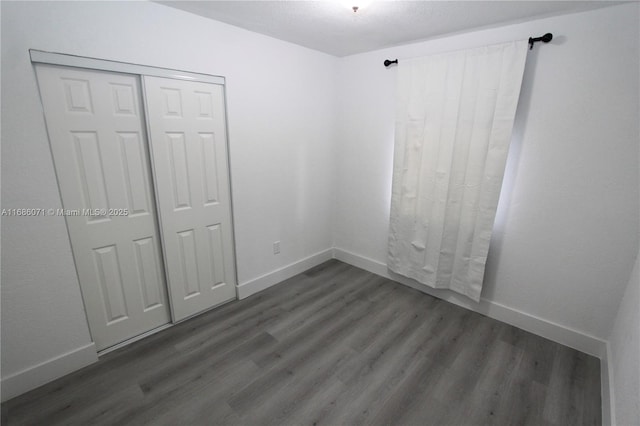 unfurnished bedroom featuring a closet and dark hardwood / wood-style floors