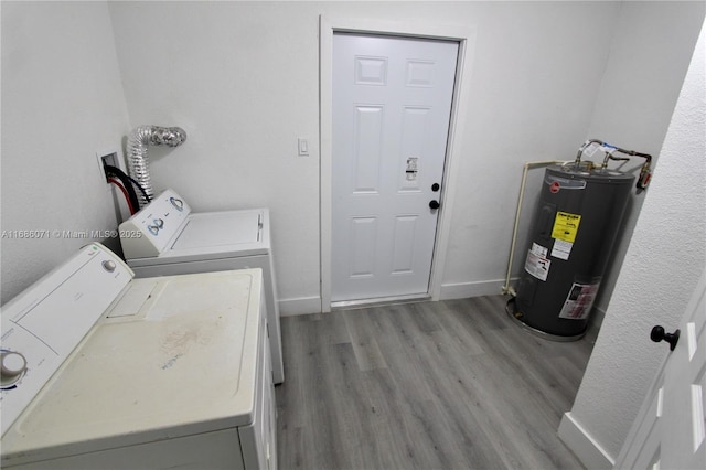 clothes washing area featuring washing machine and dryer, light hardwood / wood-style floors, and water heater