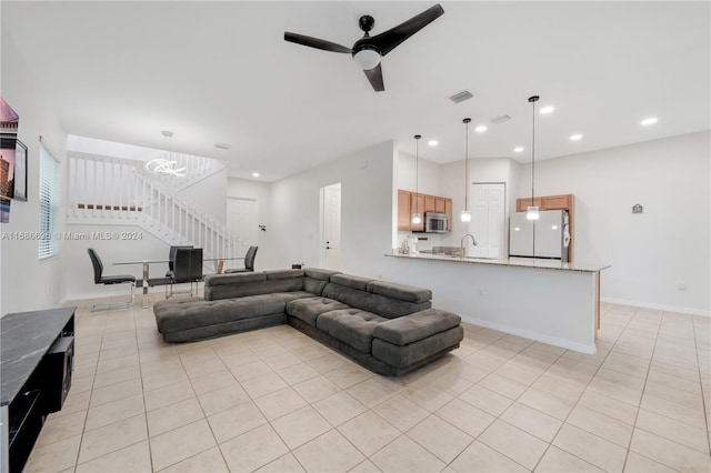 living room featuring sink, ceiling fan with notable chandelier, and light tile patterned floors