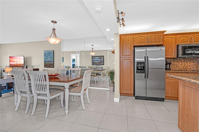 kitchen featuring decorative light fixtures, light tile patterned floors, stone counters, appliances with stainless steel finishes, and tasteful backsplash