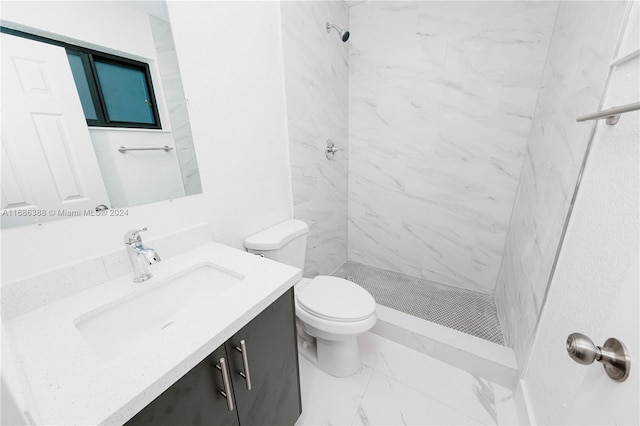 bathroom with vanity, tiled shower, and toilet