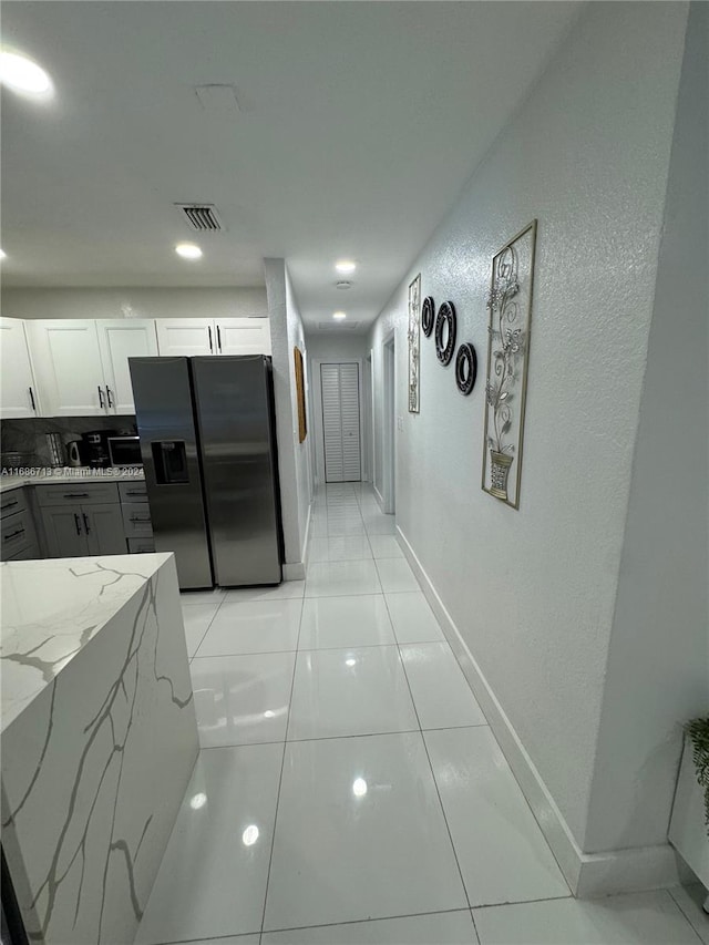 kitchen with light stone counters, light tile patterned floors, gray cabinetry, white cabinetry, and stainless steel fridge