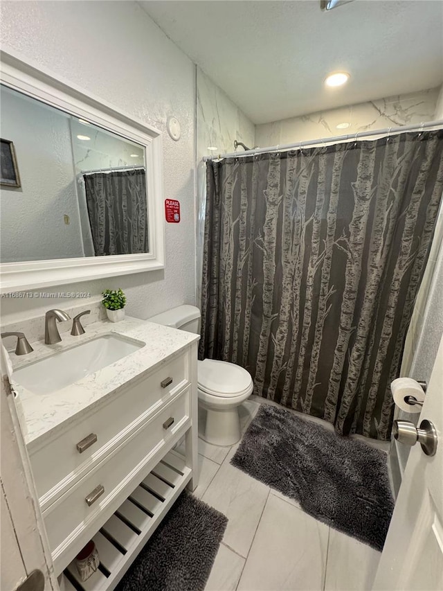 bathroom with walk in shower, vanity, and toilet