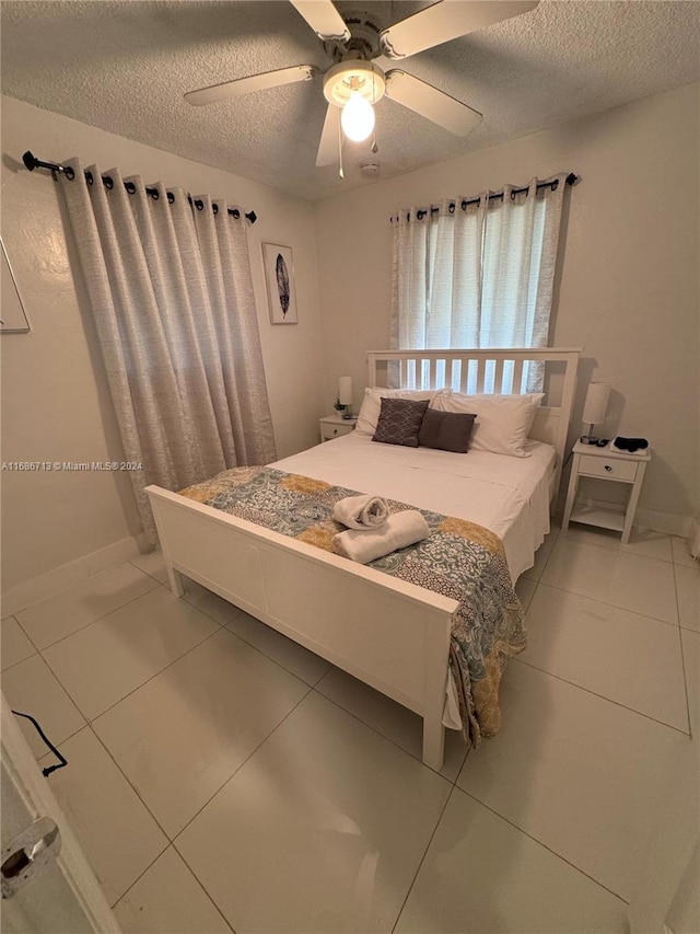 tiled bedroom with a textured ceiling and ceiling fan