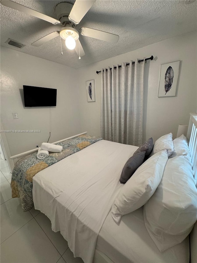 bedroom featuring a textured ceiling, ceiling fan, and tile patterned floors