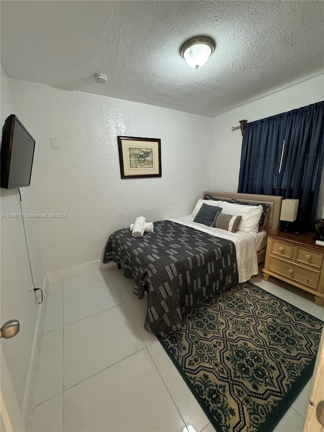 bedroom with a textured ceiling and tile patterned floors