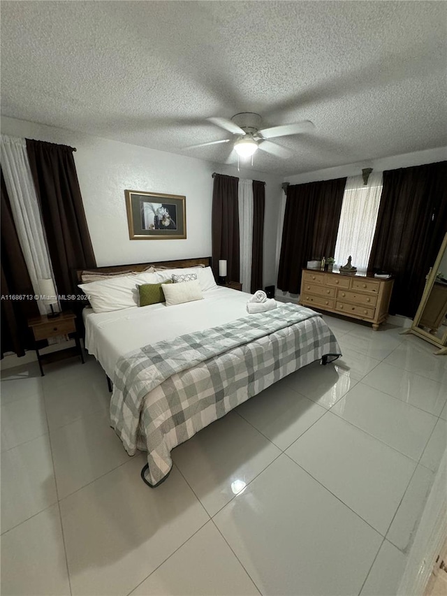 bedroom with a textured ceiling, ceiling fan, and light tile patterned floors