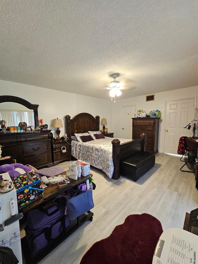 bedroom with a textured ceiling, light hardwood / wood-style floors, and ceiling fan