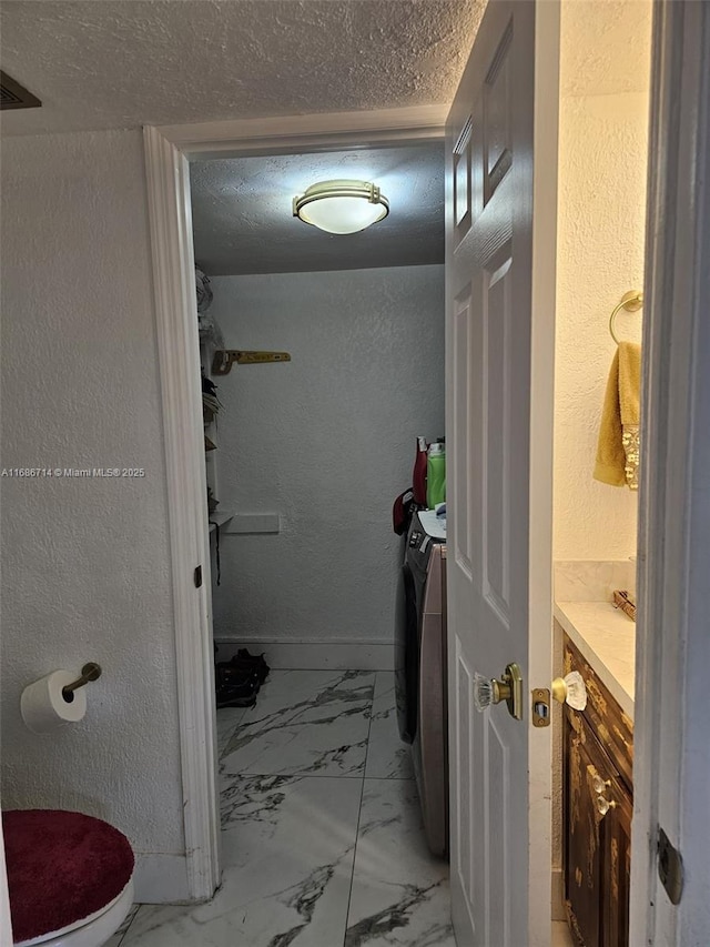 bathroom featuring vanity, washer and dryer, and toilet