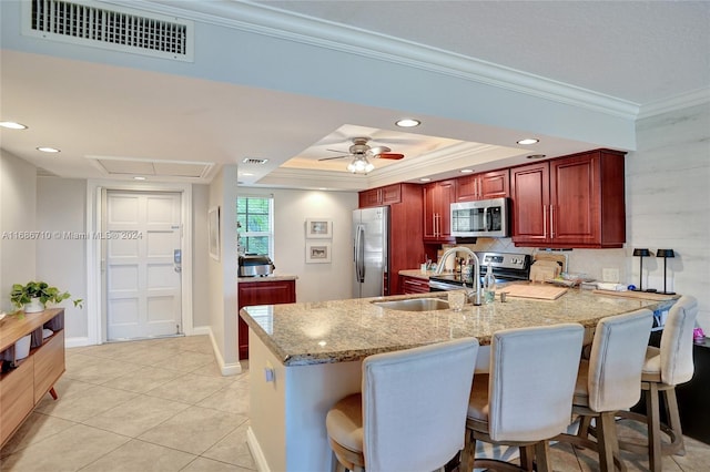 kitchen featuring kitchen peninsula, a breakfast bar, light stone countertops, ornamental molding, and stainless steel appliances