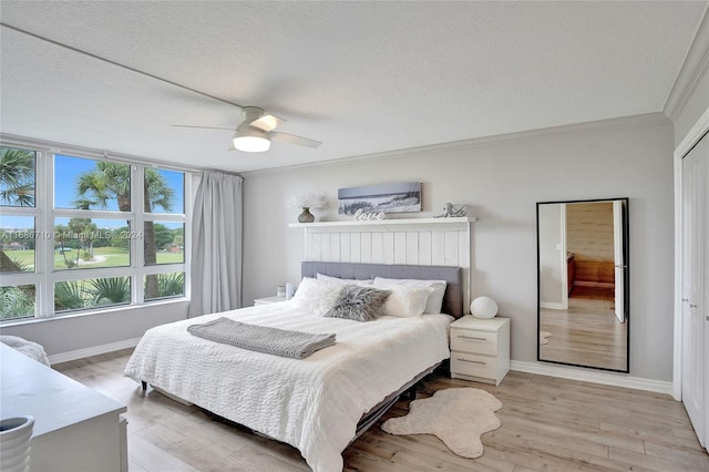 bedroom featuring a closet, crown molding, light wood-type flooring, a textured ceiling, and ceiling fan